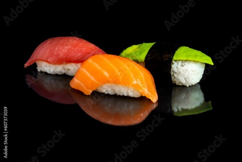 Mackerel, salmon and avocado sushis isolated on a black background.