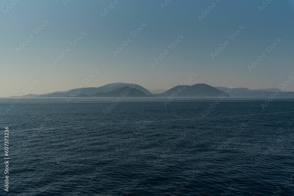 Seascape view at sunrise with misty mountains and clear sky background