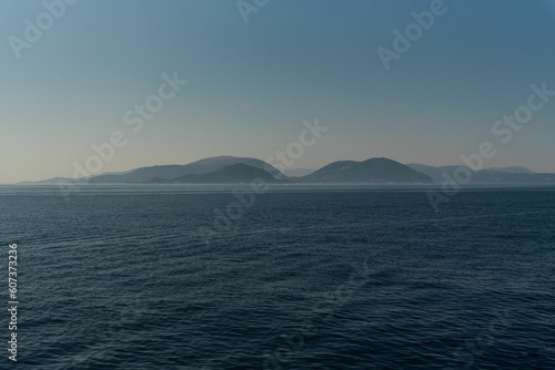 Seascape view at sunrise with misty mountains and clear sky background