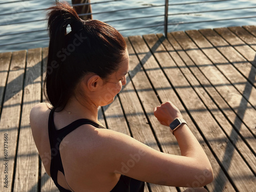 A smart watch on your hand for counting calories. A sporty woman does exercises in the open air. The trainer is engaged in fitness on the street.Healthy lifestyle, sports activities in the city.