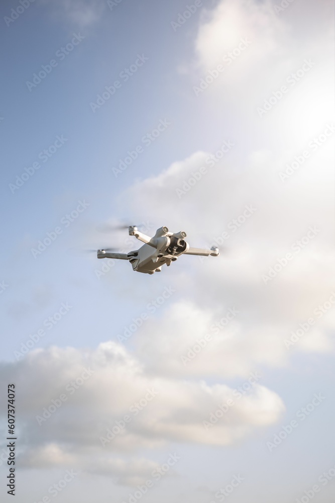 Vertical shot of a quadcopter flying in the sky in a sunny day Vertical shot of a quadcopter flying in the sky in a sunny day