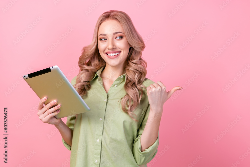 Photo of charming girl use tablet look direct finger empty space offer ad isolated on pink color background Photo of charming girl use tablet look direct finger empty space offer ad isolated on pink color background