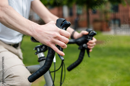 Close-up of hands on handlebar bike in park.