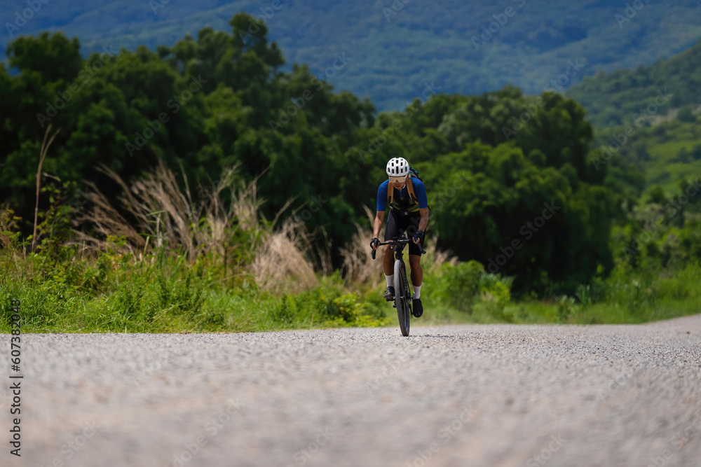 Asian male cyclist riding bicycle on gravel road