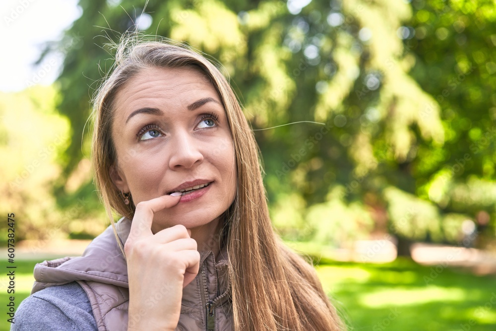 Middle-aged woman in a park on a sunny day smiling and raising thumb up Middle-aged woman in a park on a sunny day smiling and raising thumb up