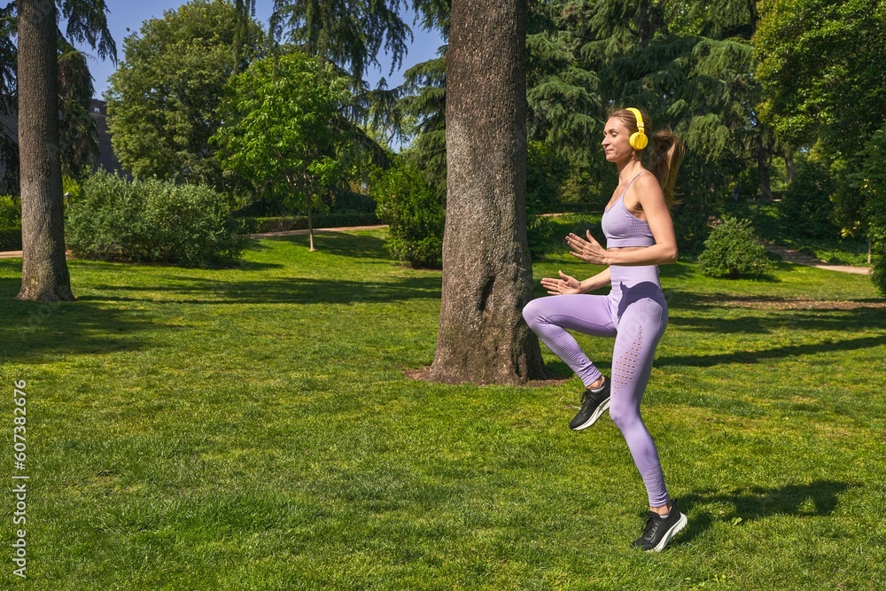 In sportswear, a woman in the park warms up, her commitment to fitness clear.