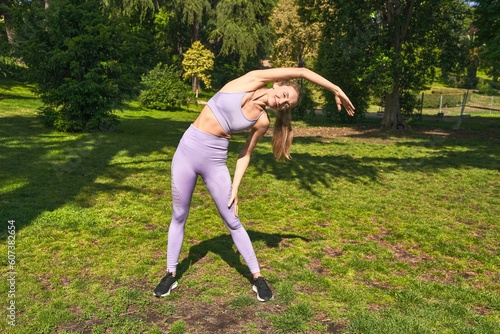 In sportswear, a woman stretches, her commitment to fitness echoed in the park.
