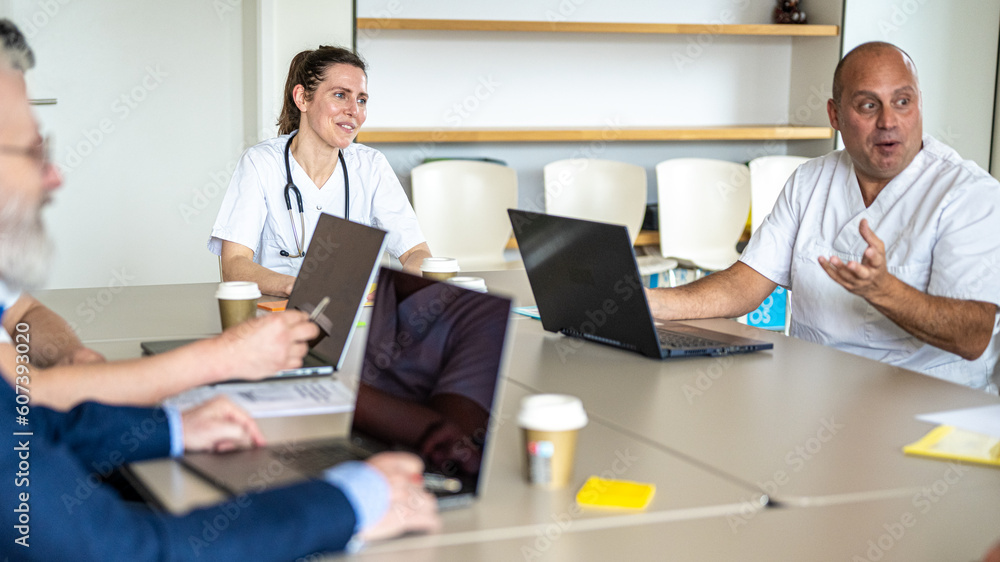 Fototapeta premium Moment of technical meeting in a medical clinic between doctors and assistants, round table of discussion between medical staff, consullta on the future operations and scheduled interventions