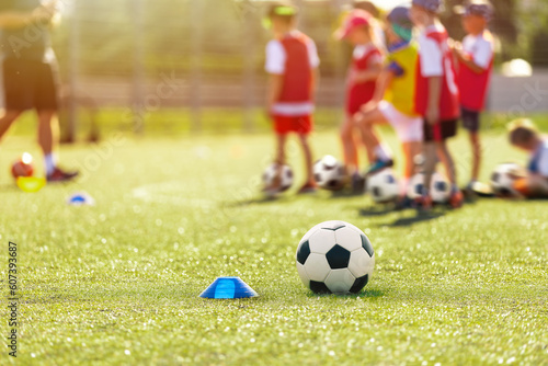 Soccer, training and children on sports field. Football equipment at sports grass pitch. Soccer ball and training cone marker on the pitch. Children on sports practice