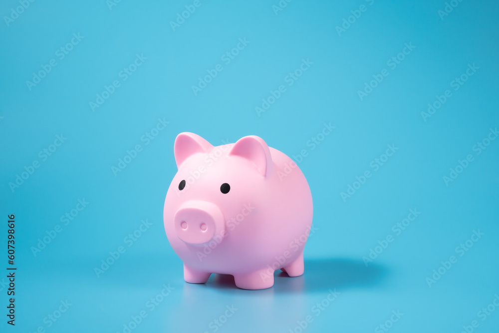 A pink piggy bank on blue background with copy space.