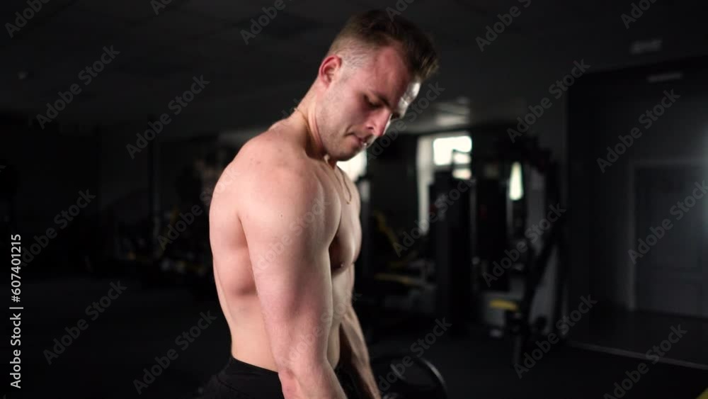 Male bodybuilder posing and showing his muscles to the camera in a gym with exercise equipment Male bodybuilder posing and showing his muscles to the camera in a gym with exercise equipment