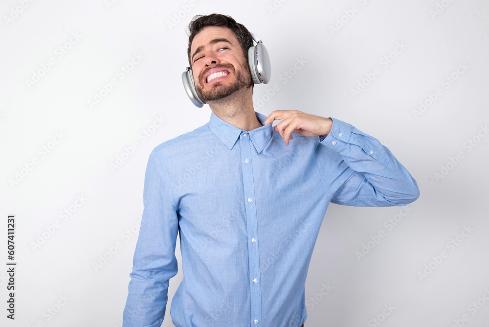 businessman wearing blue t-shirt with headphones over white background stressed, anxious, tired and frustrated, pulling shirt neck, looking frustrated with problem businessman wearing blue t-shirt with headphones over white background stressed, anxious, tired and frustrated, pulling shirt neck, looking frustrated with problem