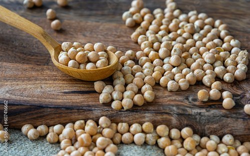 raw chickpeas in a wooden spoon on a rustic wooden cutting board close-up.