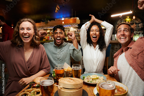 Happy young multiracial group of friends in casual clothing celebrating with dinner and drinks at restaurant