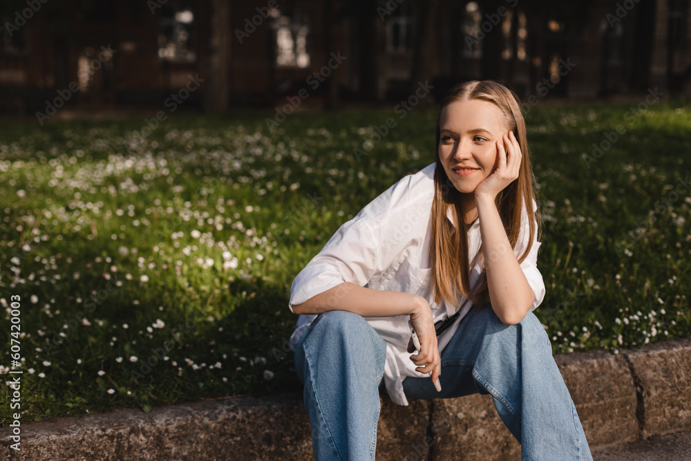 Portrait of beautiful confident woman smiling in nature, walk in park and look by side. Happy blonde woman look by side, enjoy of nature, amazement woman in white shirt and blue jeans. Girl hold head. Portrait of beautiful confident woman smiling in nature, walk in park and look by side. Happy blonde woman look by side, enjoy of nature, amazement woman in white shirt and blue jeans. Girl hold head.