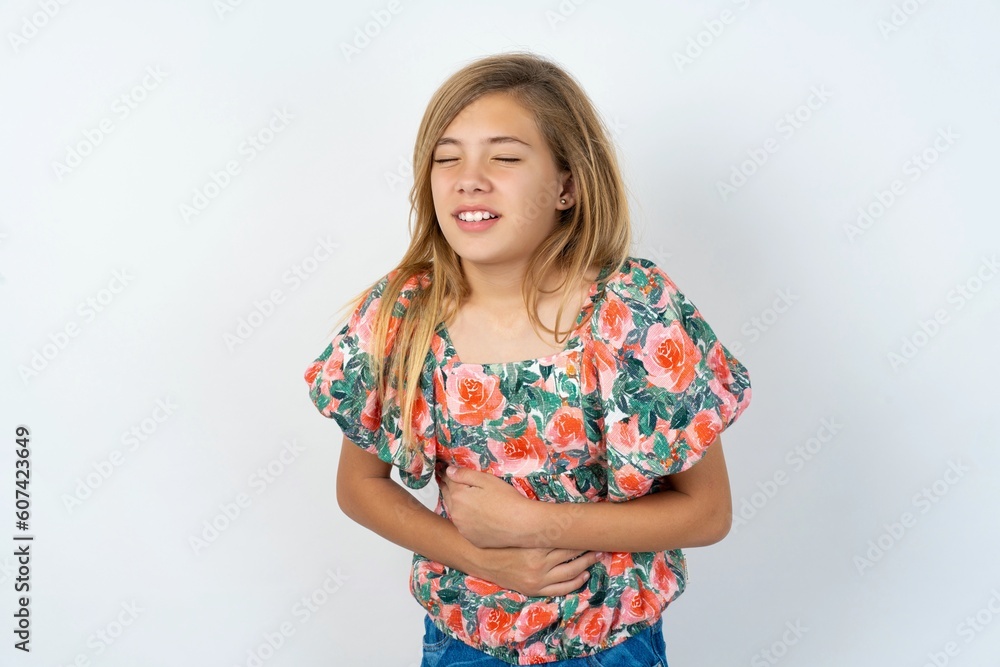 beautiful teen girl wearing flowered dress over white studio background with hand on stomach because nausea, painful disease feeling unwell. Ache concept. beautiful teen girl wearing flowered dress over white studio background with hand on stomach because nausea, painful disease feeling unwell. Ache concept.