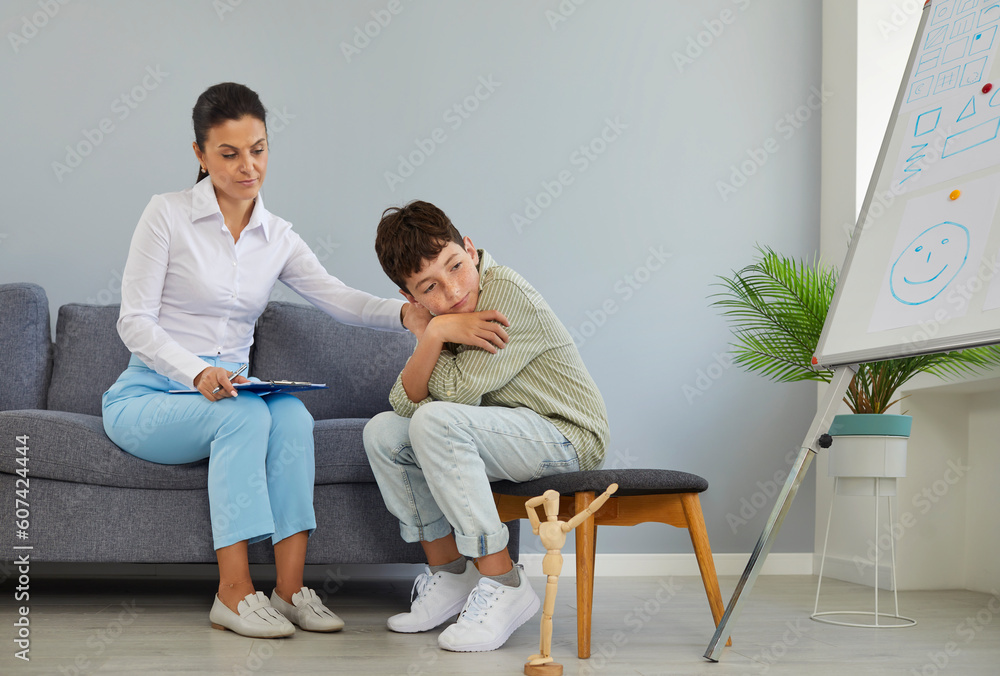 Professional psychologist talking to school child. Specialist having conversation session with depressed little boy, trying to understand his problems and troubles and comfort him. Psychology concept Professional psychologist talking to school child. Specialist having conversation session with depressed little boy, trying to understand his problems and troubles and comfort him. Psychology concept