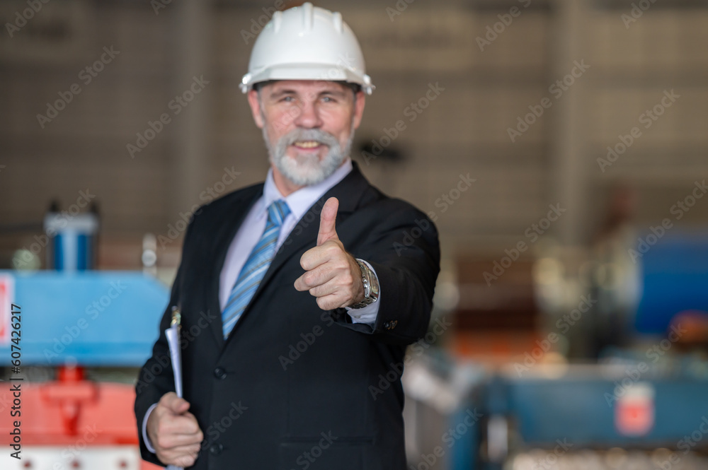 older owner engineer with beard mustache on face standing smile with his arms crossed at construction factory site. Boss manager in suit show good thumb at factory industry site. older owner engineer with beard mustache on face standing smile with his arms crossed at construction factory site. Boss manager in suit show good thumb at factory industry site.