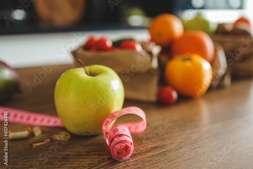 Green apple, vitamins and meter on the kitchen table, weight loss concept