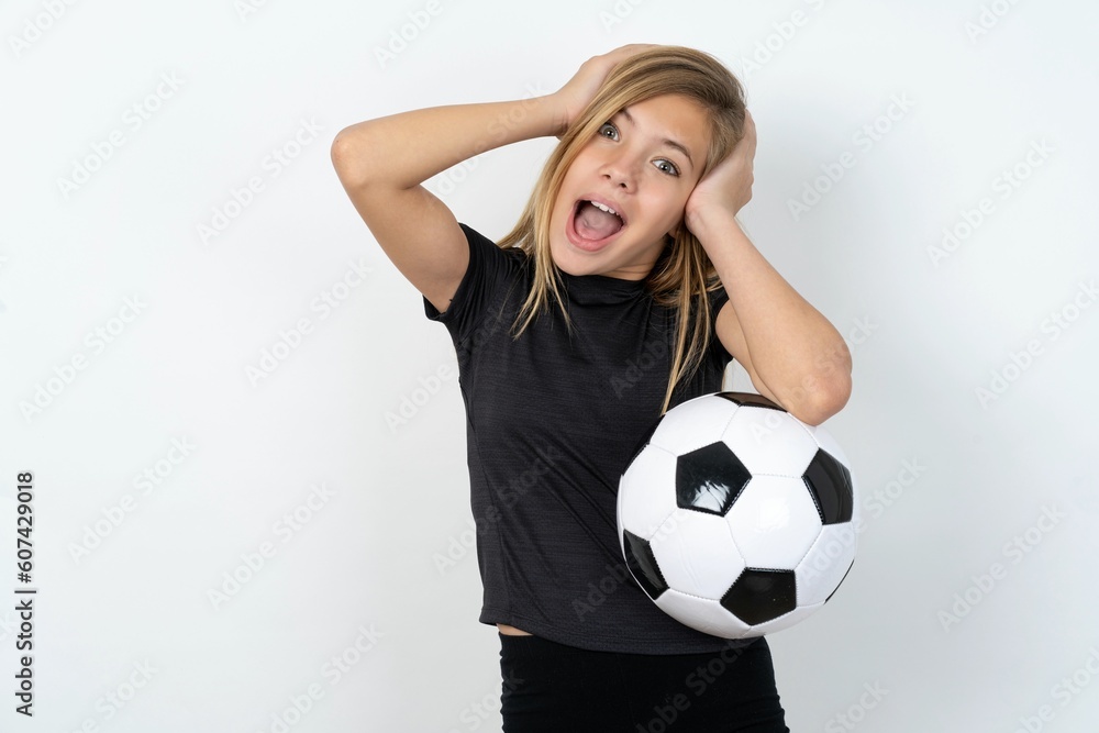 Cheerful overjoyed beautiful caucasian teen girl wearing sportswear over white wall reacts rising hands over head after receiving great news. Cheerful overjoyed beautiful caucasian teen girl wearing sportswear over white wall reacts rising hands over head after receiving great news.