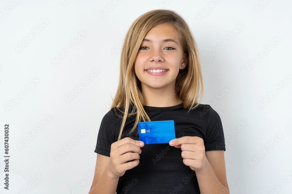 Photo of beautiful caucasian teen girl wearing sportswear over white wall positive smile hold credit card income salary Photo of beautiful caucasian teen girl wearing sportswear over white wall positive smile hold credit card income salary
