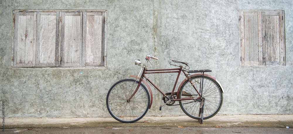 Banner panorama size of Vintage bicycle on old rustic dirty wall house, many stain on wood wall. Classic bike bicycle on decay brick wall retro style. Cement loft partition and window background.