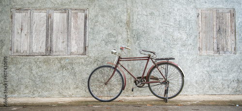 Banner panorama size of Vintage bicycle on old rustic dirty wall house, many stain on wood wall. Classic bike bicycle on decay brick wall retro style. Cement loft partition and window background. © BESTIMAGE