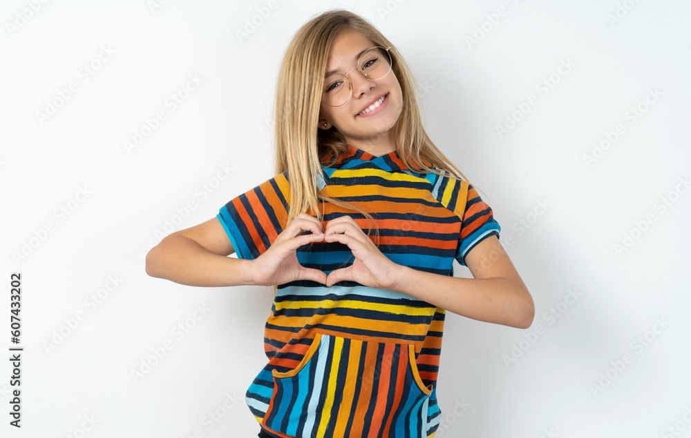 beautiful caucasian teen girl wearing striped T-shirt over white wall smiling in love showing heart symbol and shape with hands. Romantic concept. beautiful caucasian teen girl wearing striped T-shirt over white wall smiling in love showing heart symbol and shape with hands. Romantic concept.