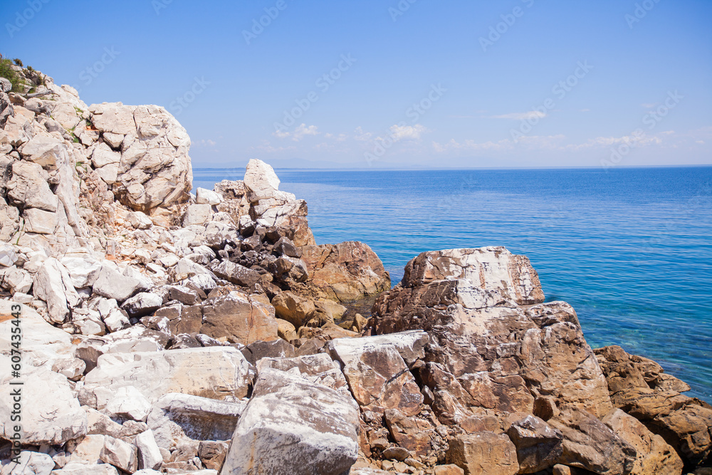  Hidden beach surrounded by rocky coastline, with an sea horizon and blue sky. Solitude and beauty in nature.
Rocks and shoreline meet beautiful sky and sea waves for a hidden, romantic getaway.