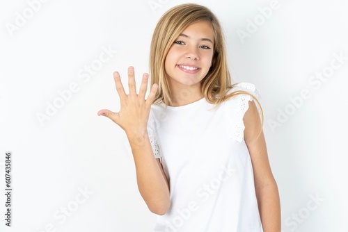 beautiful caucasian teen girl wearing white T-shirt over white wall smiling and looking friendly, showing number five or fifth with hand forward, counting down