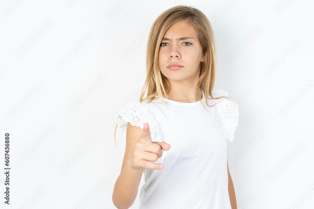beautiful caucasian teen girl wearing white T-shirt over white wall frustrated and pointing to the front beautiful caucasian teen girl wearing white T-shirt over white wall frustrated and pointing to the front