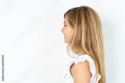 Profile portrait of nice beautiful caucasian teen girl wearing white T-shirt over white wall look empty space toothy smile