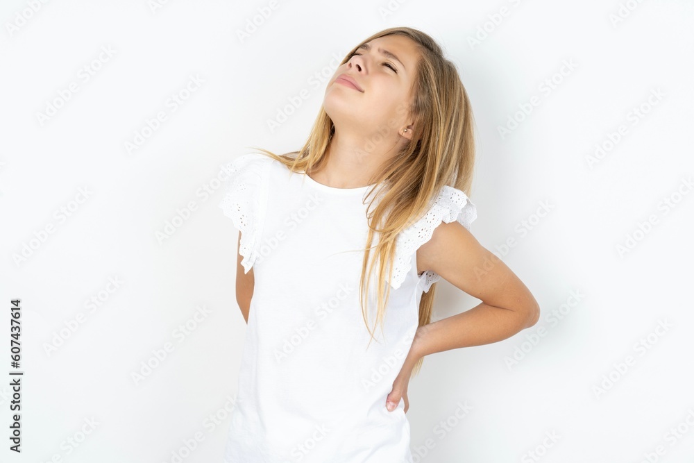 beautiful caucasian teen girl wearing white T-shirt over white wall got back pain beautiful caucasian teen girl wearing white T-shirt over white wall got back pain