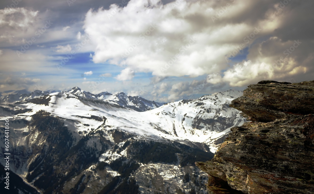 querformat, schneebedeckte berge, massive wolkenbank, blauer himmel, gebirgskette, bad hofgastein, vordergrund granitfelsen, österreich