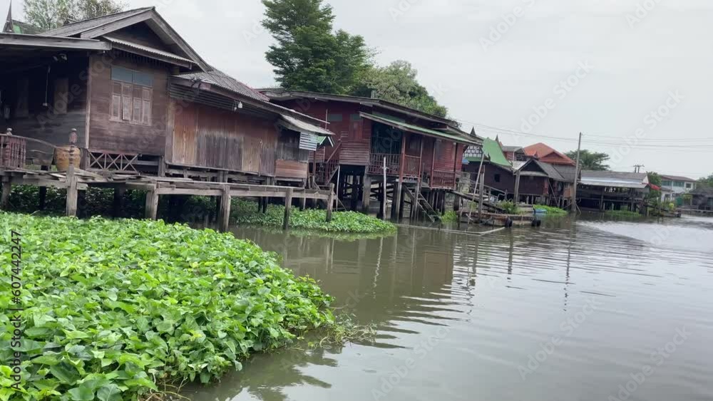 Sailing on boat towards canal slowly with view of traditional wooden Thai homes on waterfront. Point of view shot daytime. Nature concept. Thailand Sailing on boat towards canal slowly with view of traditional wooden Thai homes on waterfront. Point of view shot daytime. Nature concept. Thailand