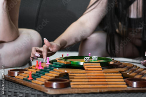 A close-up shot of the hands of two Latina friends as they move their game pieces on the Parques board.