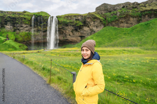 Asian tourist woman standing at front of Seljalandsfoss waterfall in summer