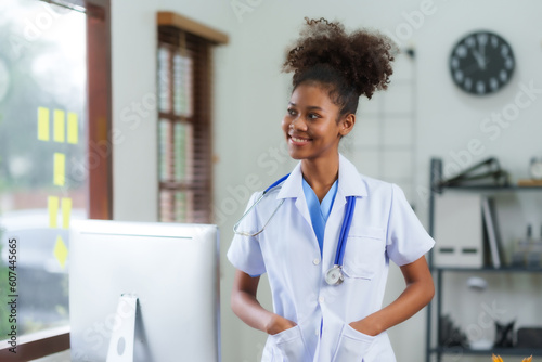 Young black woman doctor sitting and working with laptop in clinic or hospital.