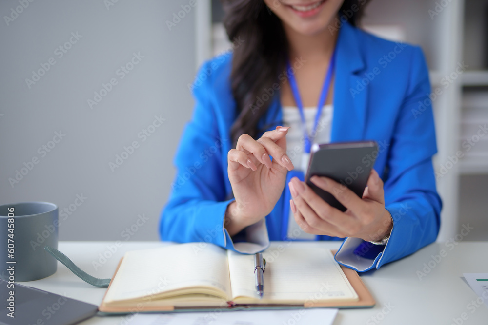 Fototapeta premium Close-up of a woman using a smartphone to work on various application including mobile transaction to send messages, LINE, and various business information sent via social media.