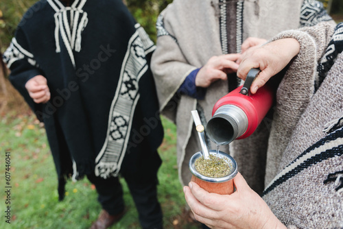 Cropped people in woolen ponchos sharing hot tea in park photo