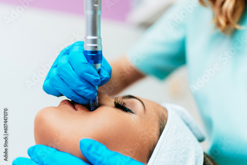 Professional cosmetologist making mesotherapy injection with dermapen on face for effective skin rejuvenation. Modern cosmetology spa treatment. photo