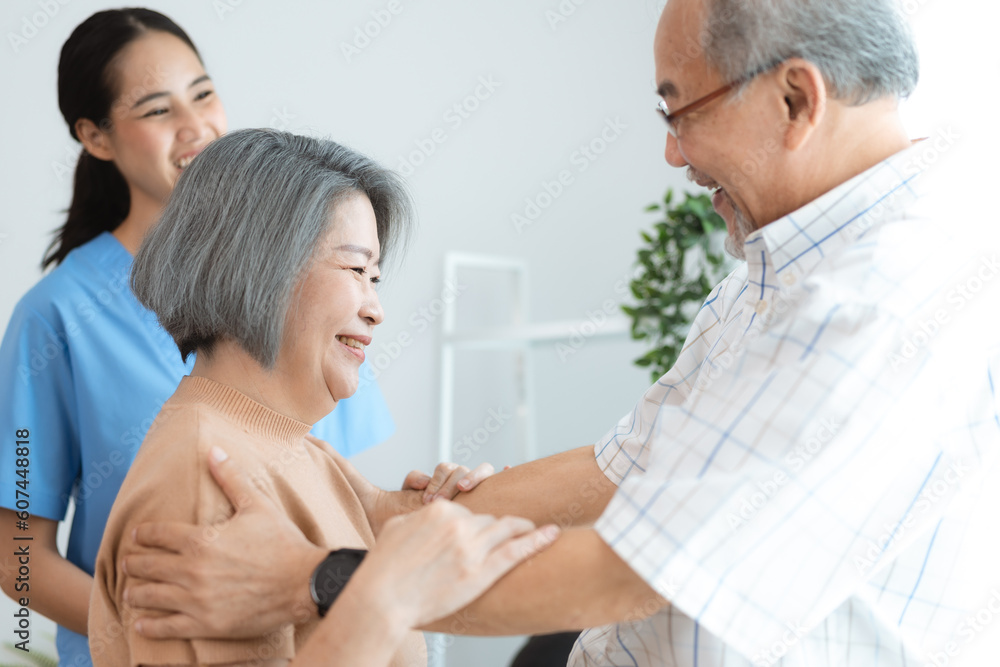 Fototapeta premium Asian senior couple in love laughing, Happy adult mature classy couple hugging and bonding, Carefree cheerful mid age old husband embracing wife looking away dreaming at home, health insurance concept