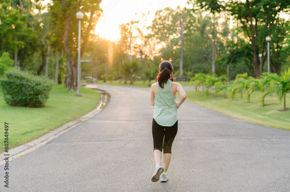 Fit Asian young woman jogging in park smiling happy running and enjoying a healthy outdoor lifestyle. Female jogger. Fitness runner girl in public park. healthy lifestyle and wellness being concept Fit Asian young woman jogging in park smiling happy running and enjoying a healthy outdoor lifestyle. Female jogger. Fitness runner girl in public park. healthy lifestyle and wellness being concept