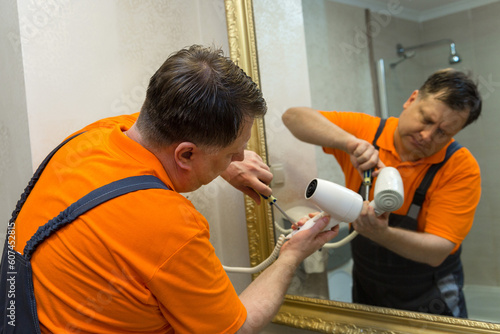 Man repairing hair dryer in bathroom.,