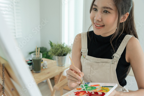 beautiful female hobbies about artist and use paintbrush in abstract art for create masterpiece. painter paint with watercolors or oil in studio house. enjoy painting as hobby, recreation, inspiration