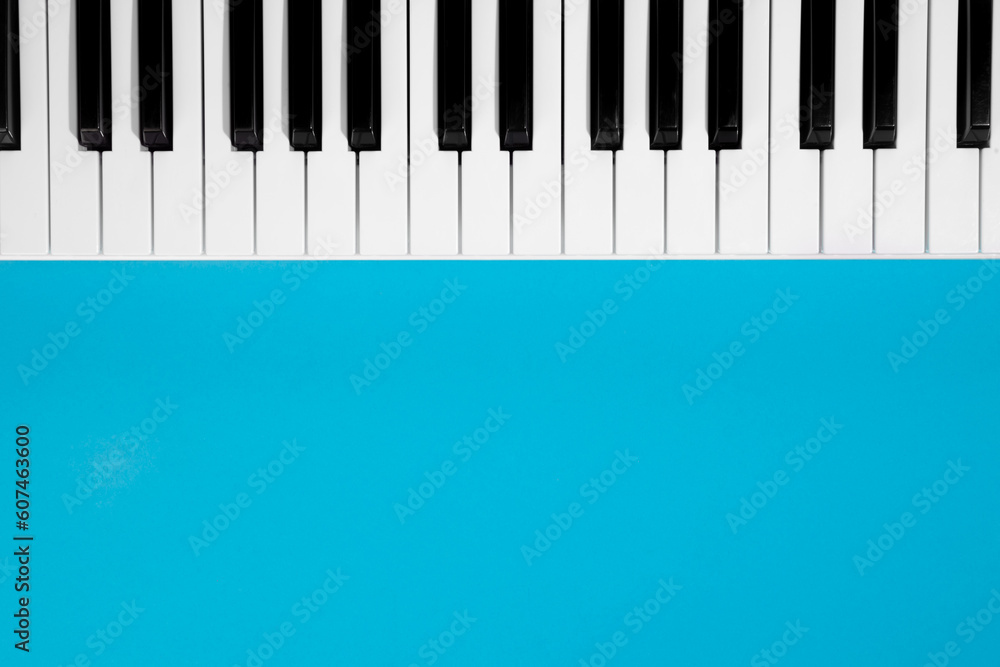 Flat lay background with piano, white synthesizer on blue background, musical keys isolated, top view, copy space. Flat lay background with piano, white synthesizer on blue background, musical keys isolated, top view, copy space.