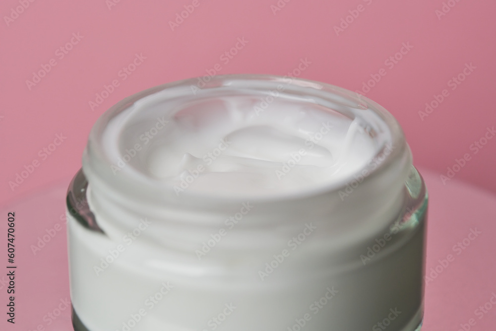 Glass jar with white face cream moisturiser on pink background. Glass jar with white face cream moisturiser on pink background.