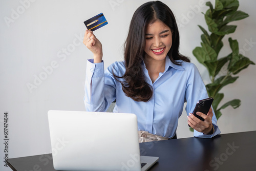 Beautiful Asian women using credit cards for shopping online with laptops and smartphones, online shopping portrait concept. photo