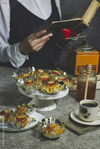 Oriental Algerian sweet cookies named dziriettes in Arabic language and honey jar, woman reading book photo