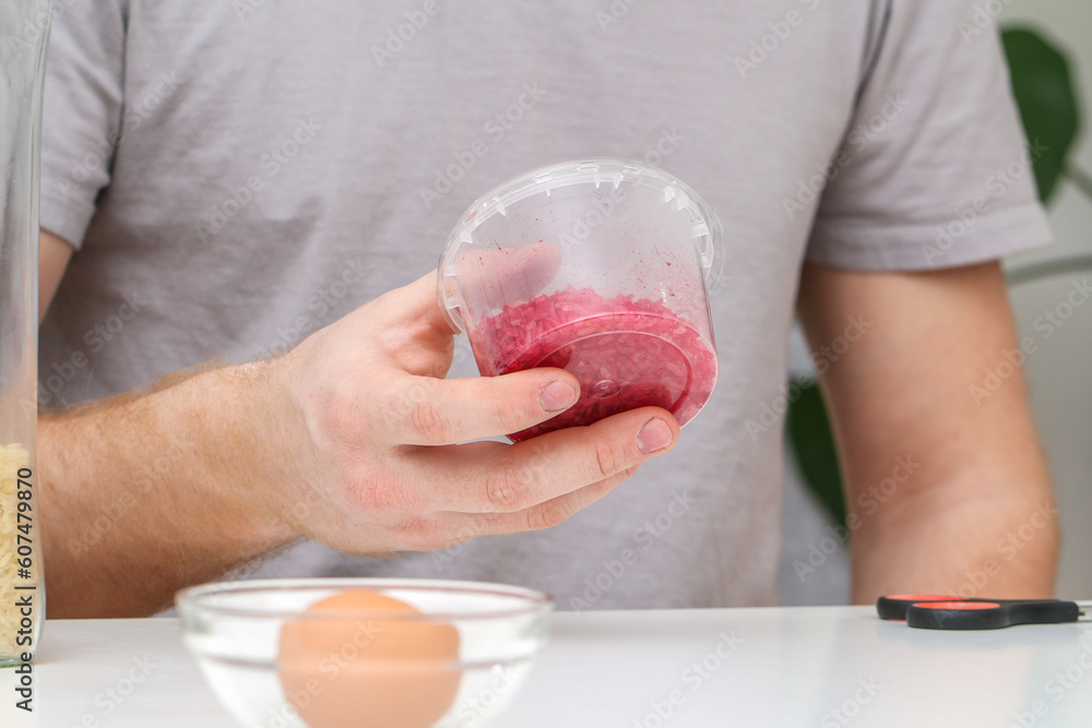 A man shakes a container of rice to evenly color the rice. An unusual way of coloring and decorating Easter eggs. Coloring Easter eggs with food dye. DIY. A man shakes a container of rice to evenly color the rice. An unusual way of coloring and decorating Easter eggs. Coloring Easter eggs with food dye. DIY.